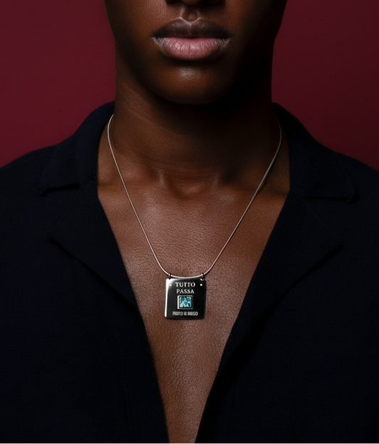 Person wearing a necklace with a pendant against a dark background